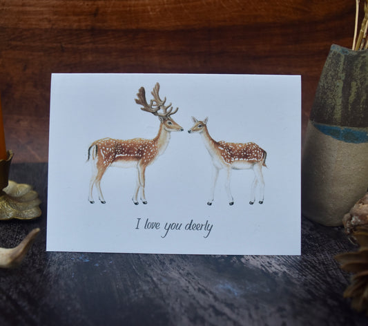 Card with two deer illustrations and 'I love you dearly' text on a wooden surface.